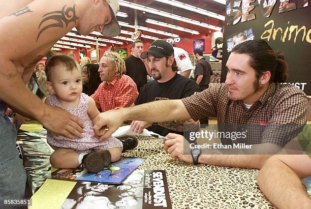 Daniel Pauling holds his 1-year-old daughter Haley Pauling as members of the rock band Sevendust, drummer Morgan Rose and guitarists John Connolly...