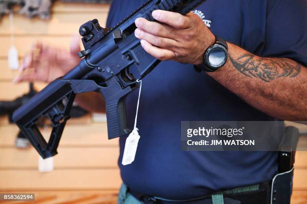 Senior Sales Staff Mark Warner shows a bump stock installed on an AR-15 rifle at Blue Ridge Arsenal in Chantilly, Virgina, on October 6, 2017.