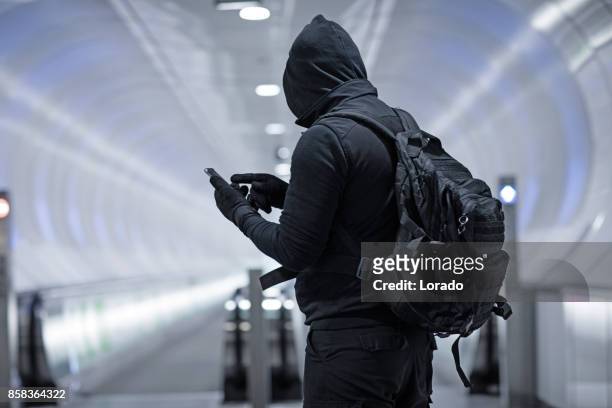 hooded lone wolf man dragen zwarte draagtas in stadsvervoer ondergrondse openbare instelling - terrorist stockfoto's en -beelden