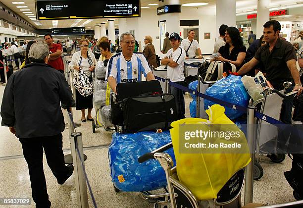 Passengers wait in the ABC Charters line to check into their American Eagle flight to Holguin, Cuba at Miami International Airport on April 7, 2009...