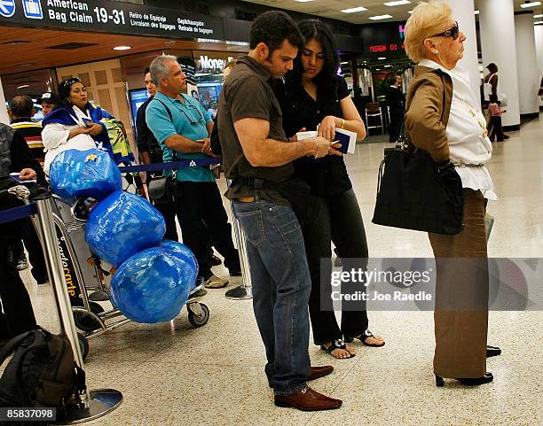 Passengers wait in the ABC Charters line to check into their American Eagle flight to Holguin, Cuba at Miami International Airport on April 7, 2009...