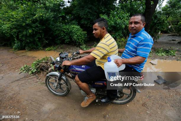 Local men carrying water bottles ride a motorbike after tropical storm Nate hit Ochomogo community, Rivas some 80 kilometres from Managua on October...