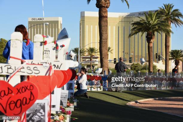 Woman prays beside 58 white crosses for the victims of Sunday night's mass shooting, on Las Vegas Strip just south of the Mandalay Bay hotel, October...