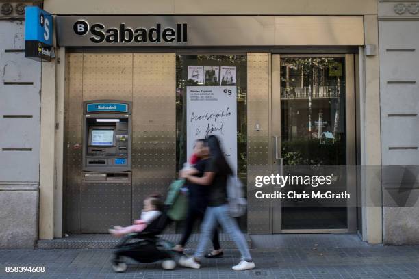 People walk past a branch of Spain's Banco de Sabadell bank on October 5, 2017 in Barcelona, Spain. Tension between the central government and the...