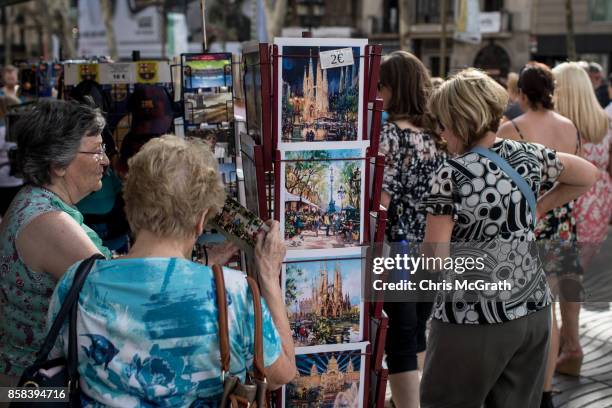 Tourists buy postcards on Barcelona's famous La Rambla street on October 6, 2017 in Barcelona, Spain. Tension between the central government and the...