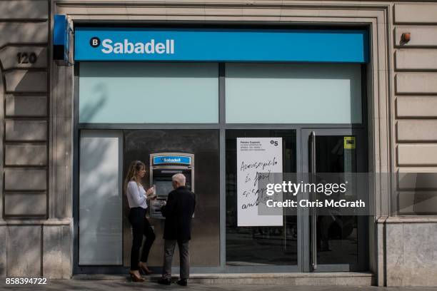 People are seen in front of a branch of Spain's Banco de Sabadell bank on October 6, 2017 in Barcelona, Spain. Tension between the central government...