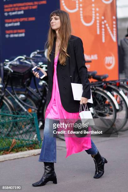 Guest wears a black jacket, a pink dress, flare jeans, black boots, outside Chanel, during Paris Fashion Week Womenswear Spring/Summer 2018, on...