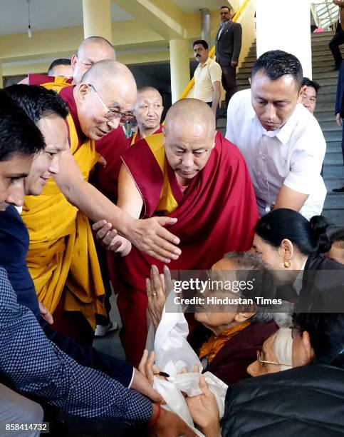 Tibetan spiritual leader the Dalai Lama, left in yellow robe, greets devotees as he arrives to give a religious talk at the Tsuglakhang Temple on...