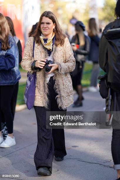 Guest wears a jacket wit fur, striped flare pants, outside Chanel, during Paris Fashion Week Womenswear Spring/Summer 2018, on October 3, 2017 in...