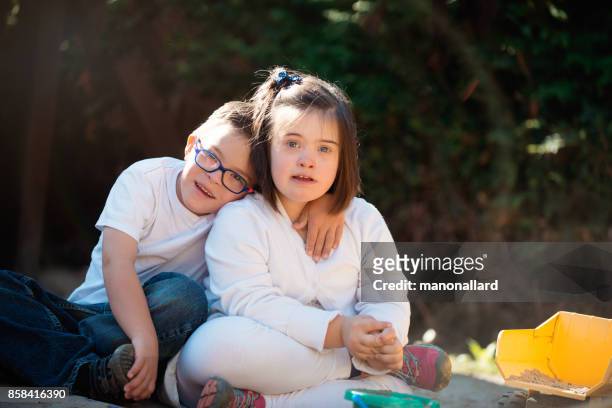 Unga syster och bror med Downs syndrom glad utomhus