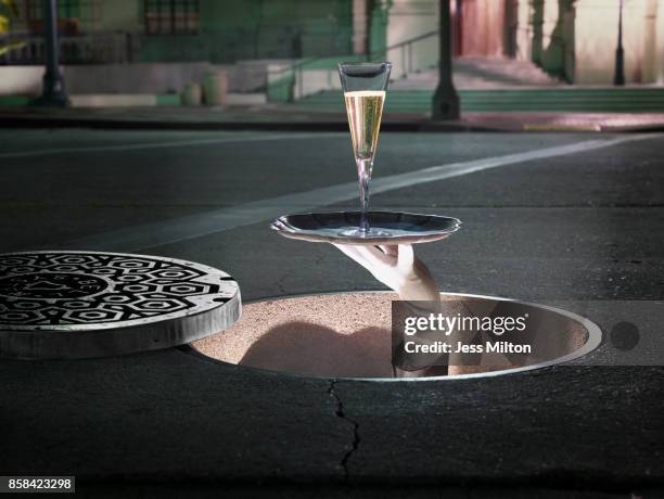 champagne flute coming out of a manhole - マンホール ストックフォトと画像