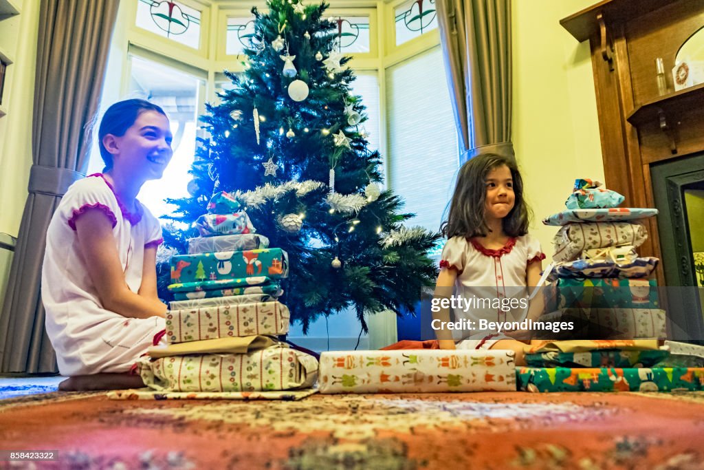 Summer Christmas: young sibling girls with presents, Xmas tree