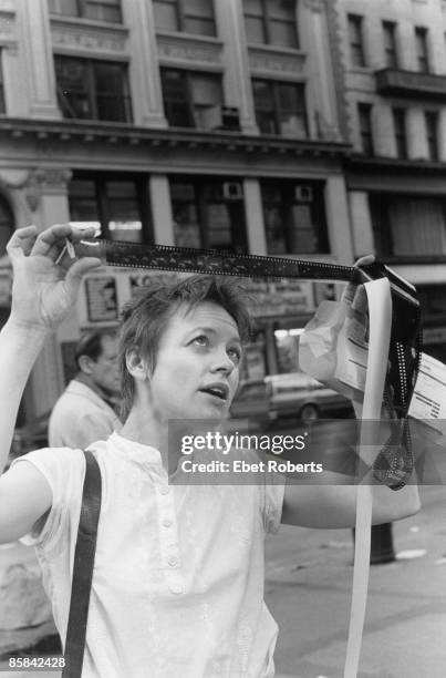 Photo of Laurie ANDERSON; Posed portrait of Laurie Anderson, looking at negative in the street