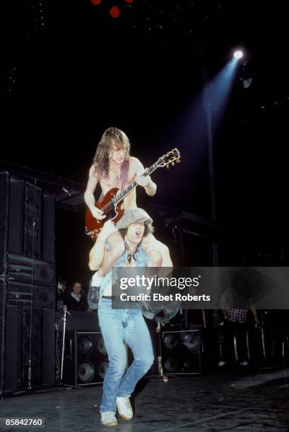 Photo of Brian JOHNSON and AC/DC and Angus YOUNG and AC DC; Angus Young playing guitar sitting on Brian Johnson's shoulders