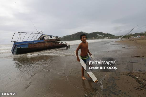 Boy collects wood from a damaged, stranded boat in San Juan del Sur beach, following the passage of Tropical Storm Nate, in Rivas some 140km from...