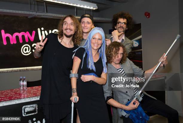 Justin Hawkins, Rufus Tiger Taylor, Frankie Poullain and Dan Hawkins of The Darkness pose with a fan and sign copies of their new album 'Pinewood...