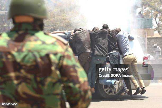 Members of opposition drive off as they hang on a vehicle after the police tear gas them whilw demonstrating in Nairobi streets, on the second week,...