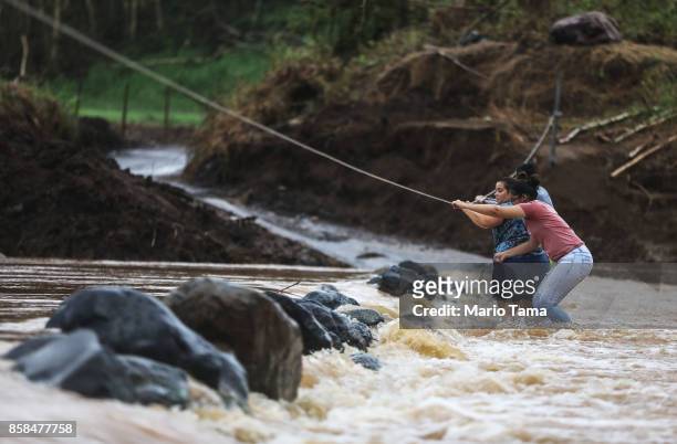 People use a rope line to cross the San Lorenzo de Morovis river more than two weeks after Hurricane Maria hit the island on October 6, 2017 in San...