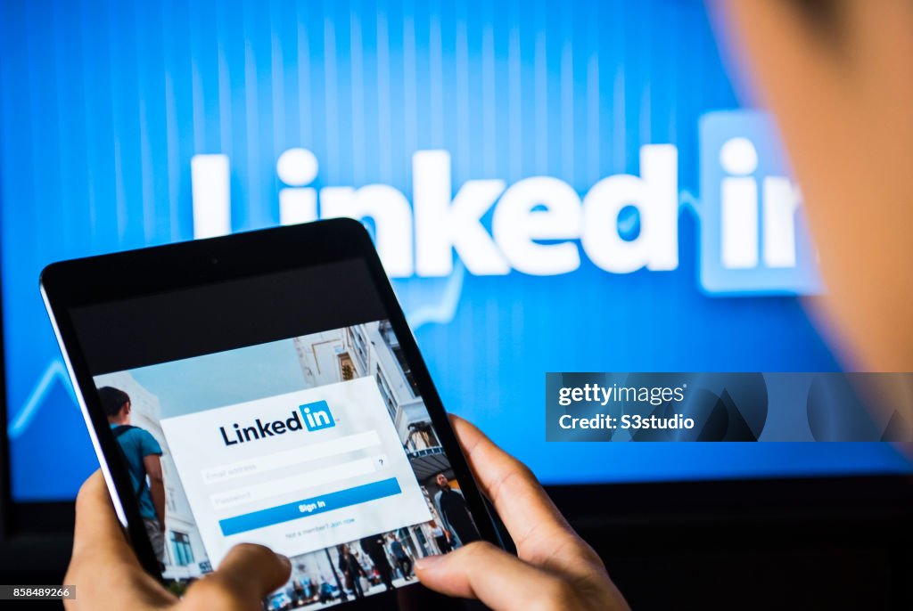 Young man holds a smart device while using Linkedin app