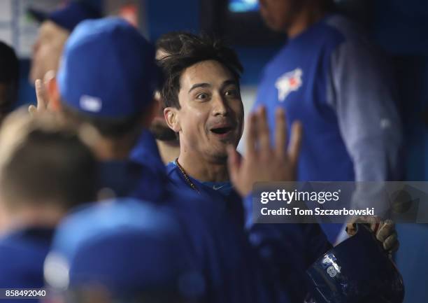 Darwin Barney of the Toronto Blue Jays reacts wryly after slipping on the basepaths earlier and is congratulated by teammates in the dugout after...