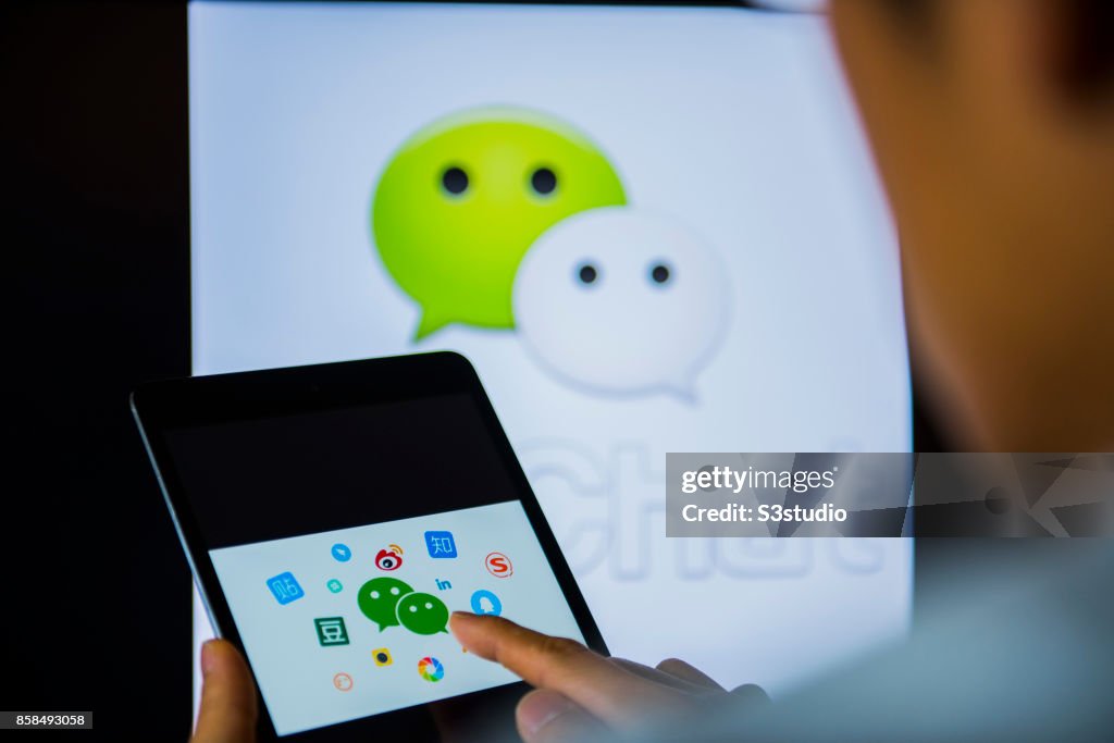 Young man holds a smart device while using WeChat app