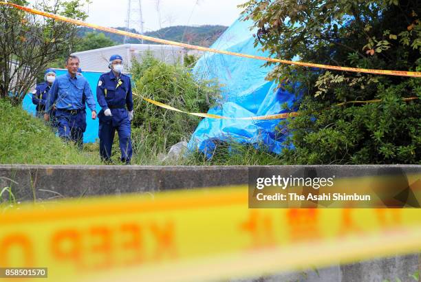 Police officers search the area around the burned-out apartment room in a prefecture-run apartment complex on October 6, 2017 in Hitachi, Ibaraki,...