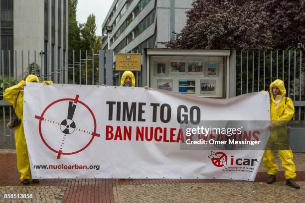 International campaign to abolish Nuclear Weapons activists wearing yellow hazmat suits and holding a banner reading 'Time to go, ban nuclear...