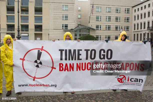International campaign to abolish Nuclear Weapons activists wearing yellow hazmat suits and holding a banner reading 'Time to go, ban nuclear...