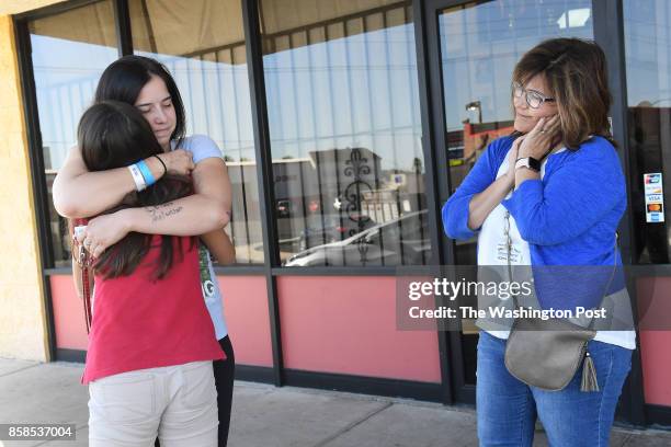 Paige Melanson hugs student, Baylee McConaghy outside the Melanson's family dance studio, Dance Dynamics as Pastor, Robyn Garcia watches at right on...