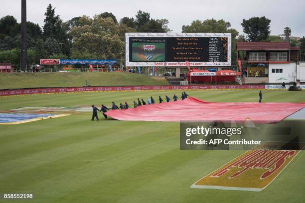 Ground staff remove the rain protection from the crease after rain delayed the beginning of the second day of the second Test Match between South...