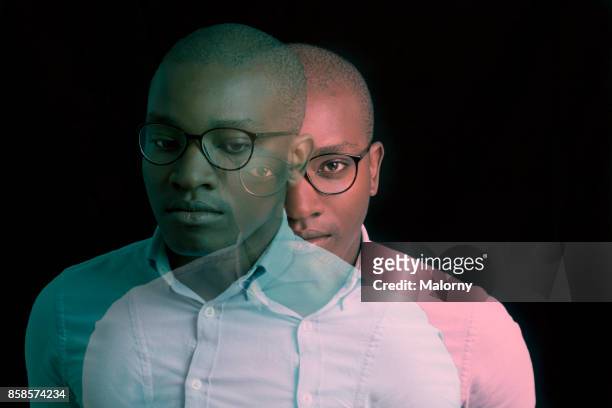 virtual reality. portrait of young man with dark skin standing in front of black background. - digital composite stock-fotos und bilder