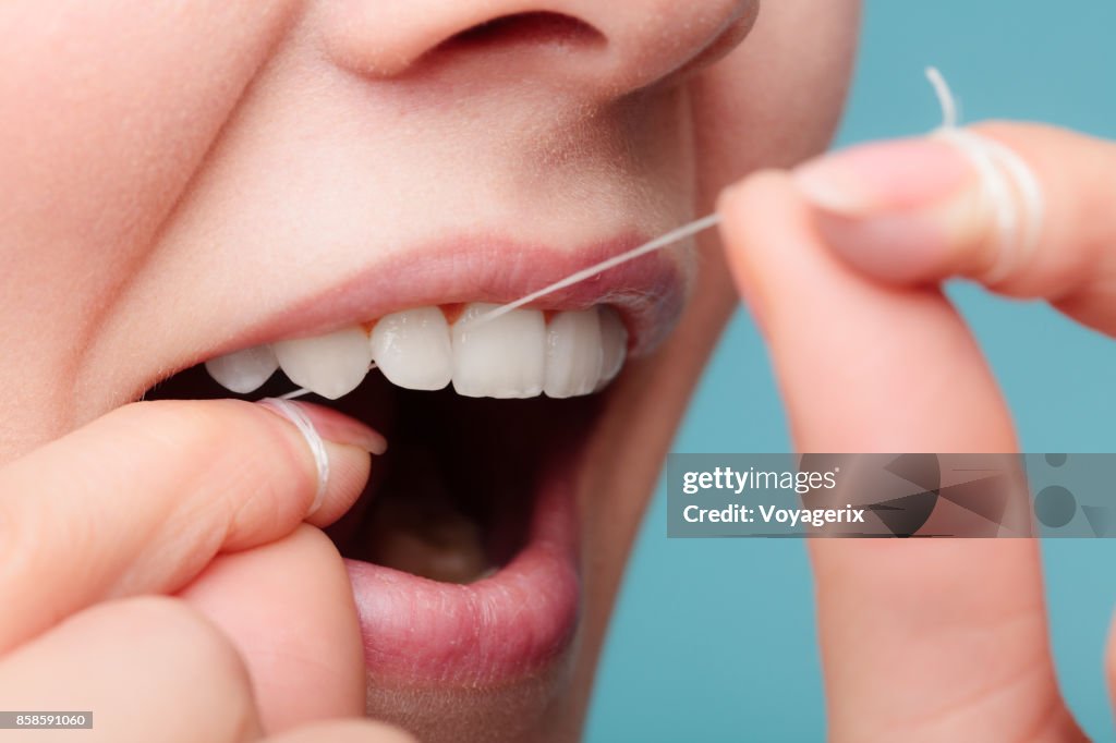 Side view woman face smiling with dental floss.