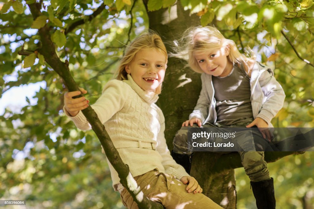 Two Beautiful young blond girl sisters together in Autumnal Park