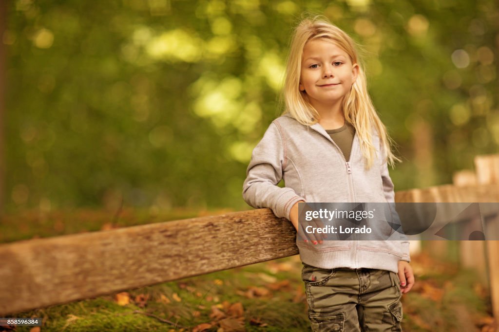 Hermosa joven rubia jugando en el parque de otoño