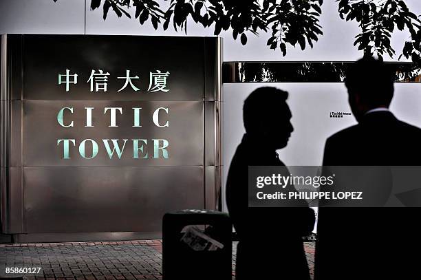 Two men chat next to the offices of CITIC Pacific in Hong Kong on April 8, 2009. CITIC Pacific Chairman Larry Yung resigned from the investment firm...