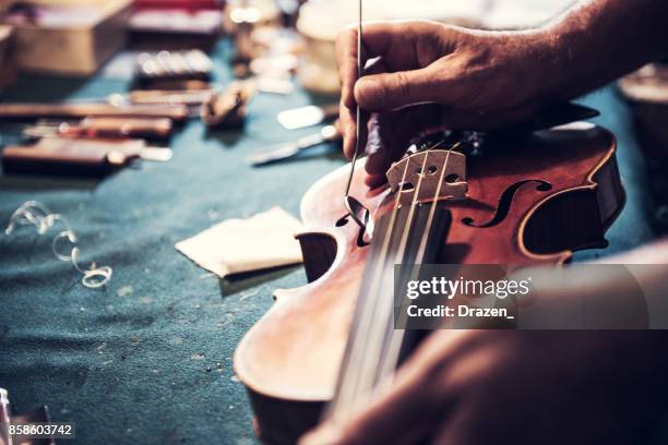 artesano principal comprobar el violín en su taller - instrument maker fotografías e imágenes de stock