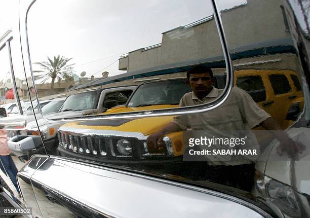 An Iraqi car dealer is reflected on the body of a Hummer at a car dealership in Baghdad on April 8, 2009. Iraqis display an unexpected demand on the...