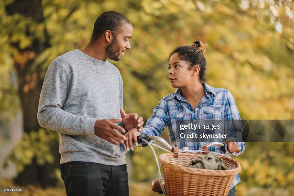 Young black couple talking to each other in the park.