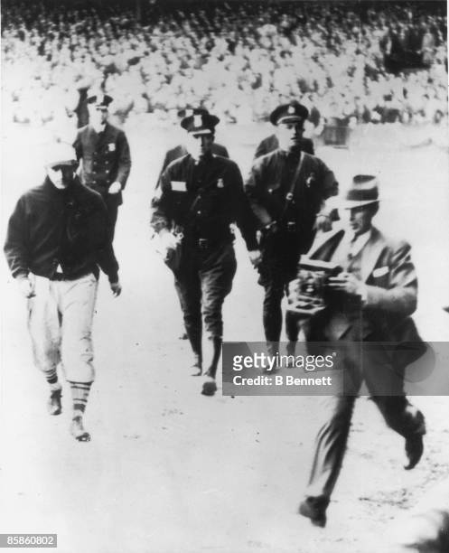 American baseball player Joe Medwick of the St. Louis Cardinals is escorted from the field by police officers during game seven of the World Series...