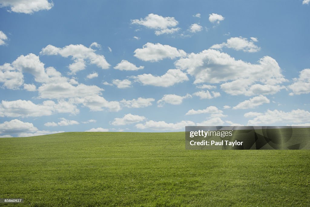 Green hill with blue sky and clouds