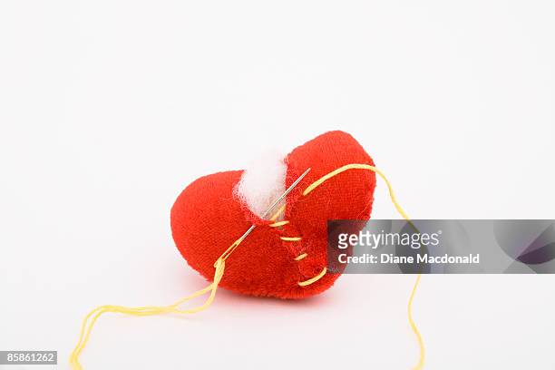 a broken heart being repaired - thread sewing item stock-fotos und bilder