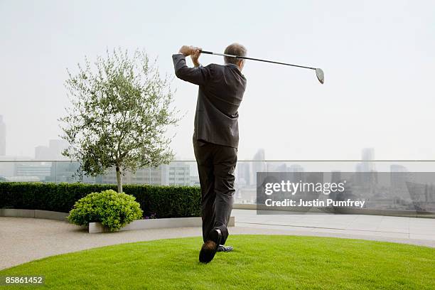 businessman playing golf on rooftop, rear view - golf swing imagens e fotografias de stock