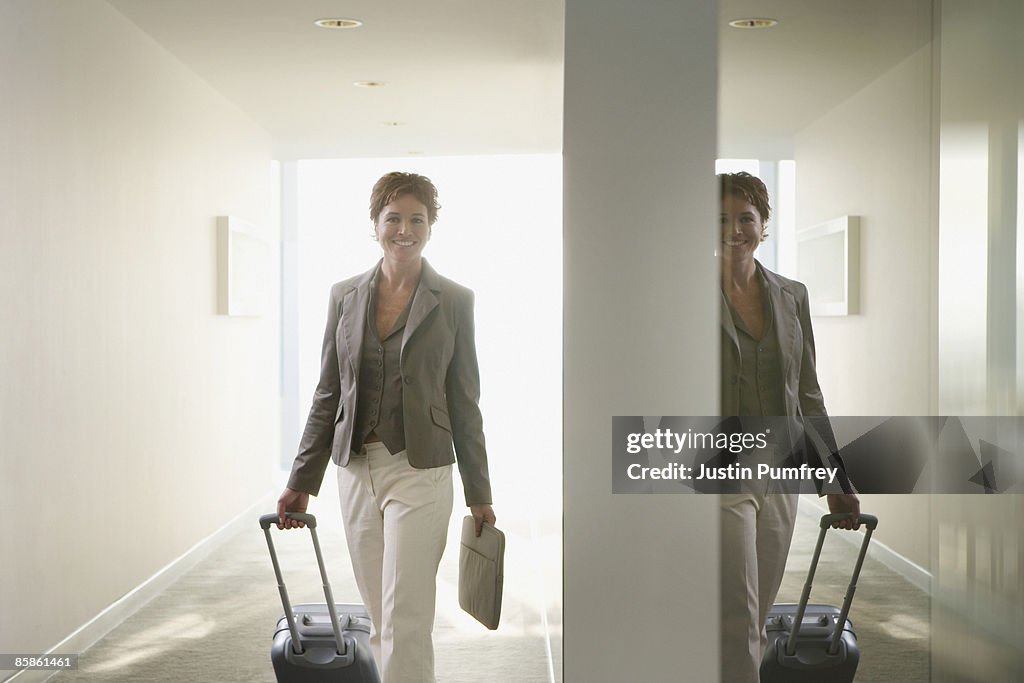 Businesswoman pulling luggage in corridor