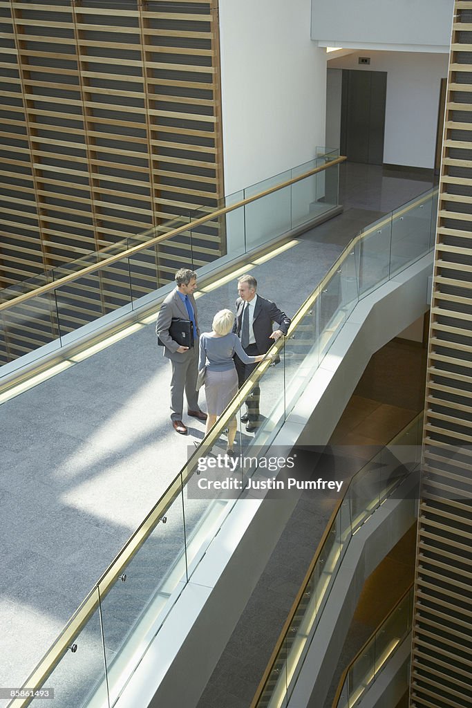 Three businesspeople talking on walkway