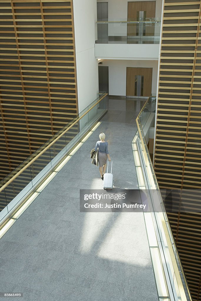 Businesswoman with luggage in modern office