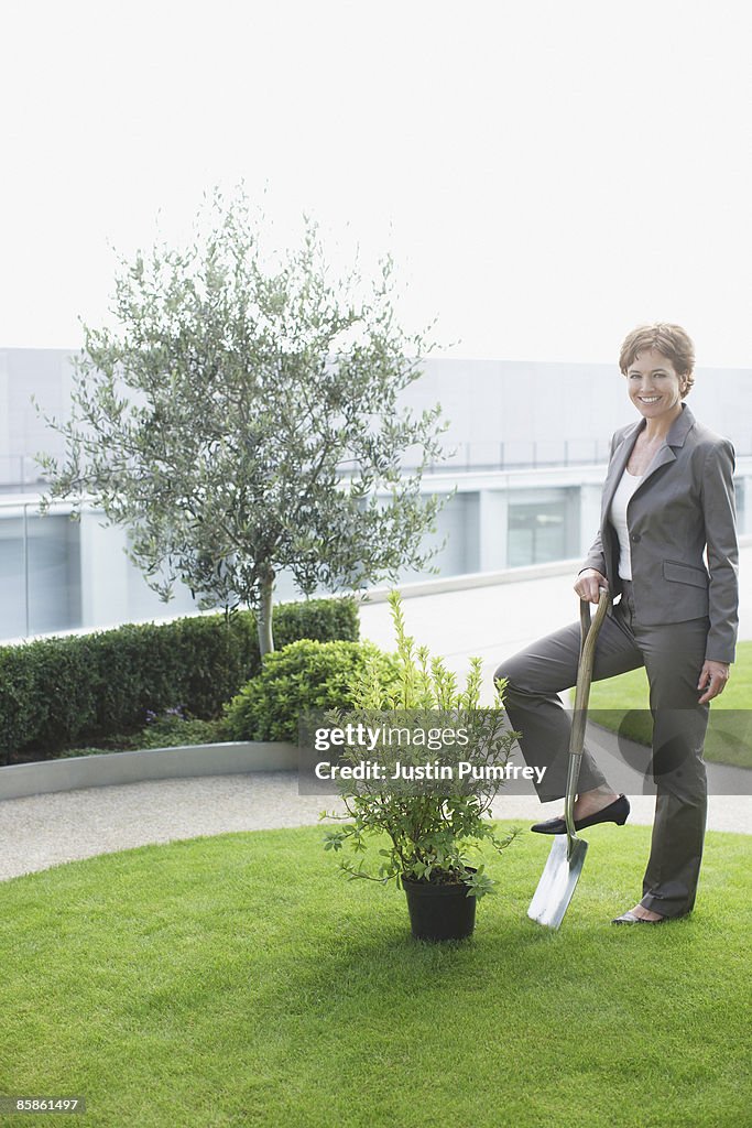 Businesswoman standing on garden spade