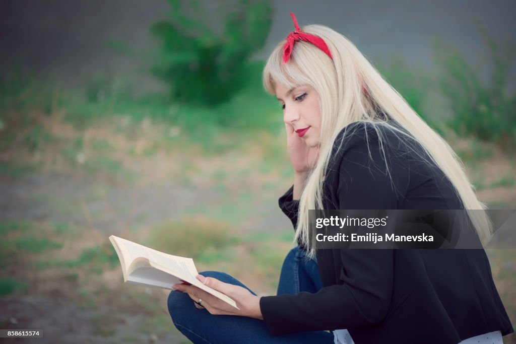 Young woman relaxing while reading a book at the park