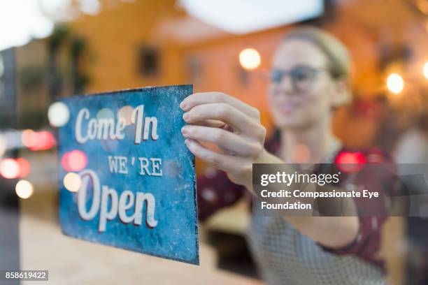 business owner setting up open sign in cafe window - compassionate eye foundation stock-fotos und bilder