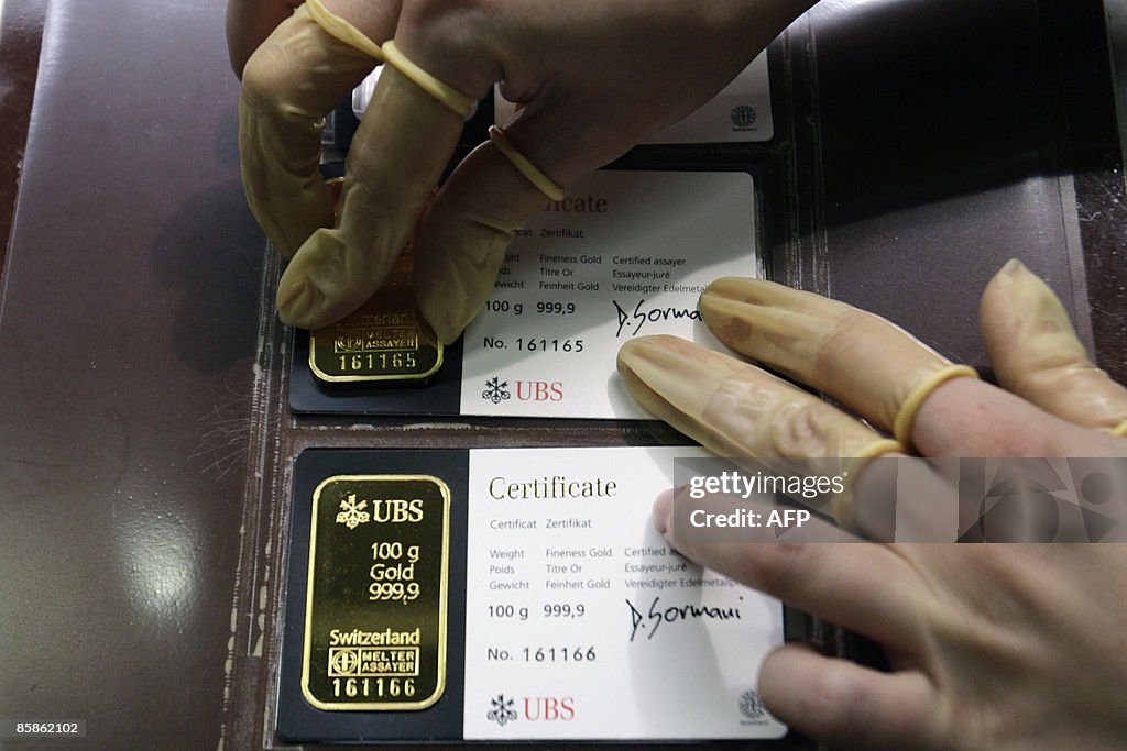 An employee arranges a 100g gold bar tog