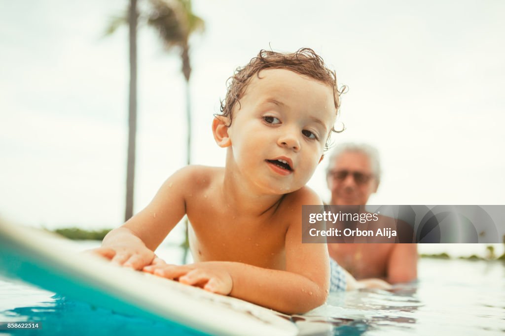 Grandfather teaching grandson to surf